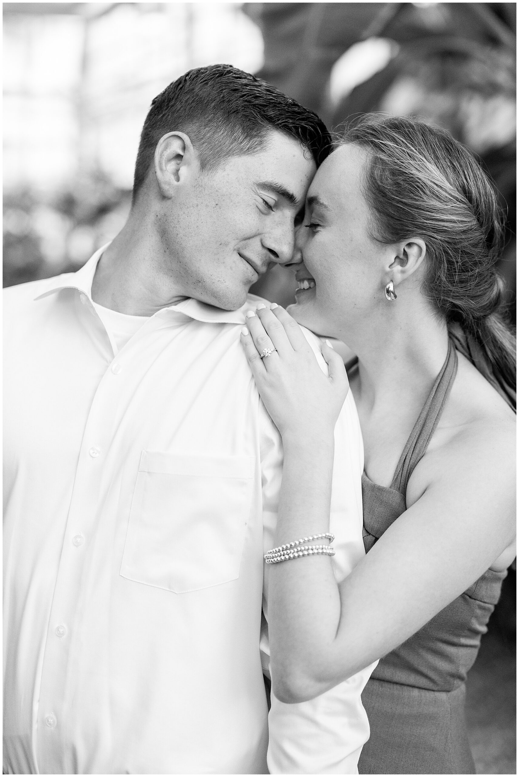 A black and white close-up image of Catherine and Jake. She places her hand on his shoulder so we can perfectly see her new engagement ring. 