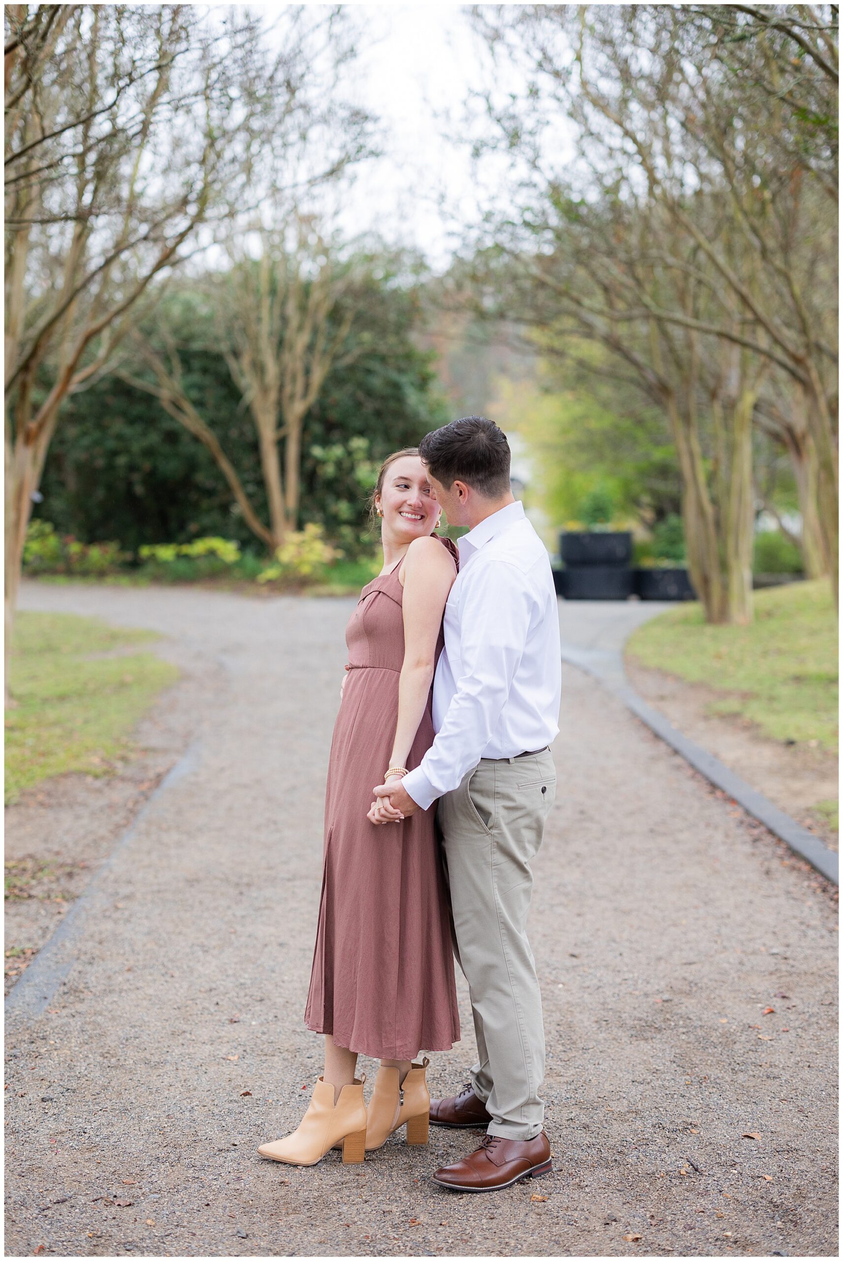 Catherine and Jake hold hands and smile at each other as they're surrounded by the trees in the Botanical Gardens. 